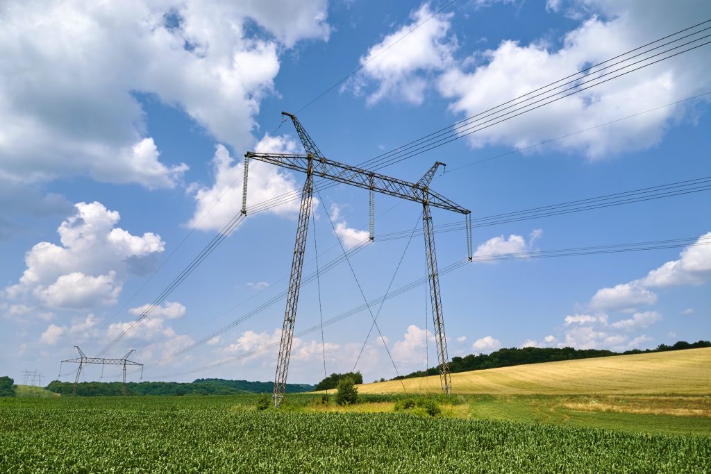 Tower with electric power lines for transfering high voltage electricity located in agricultural