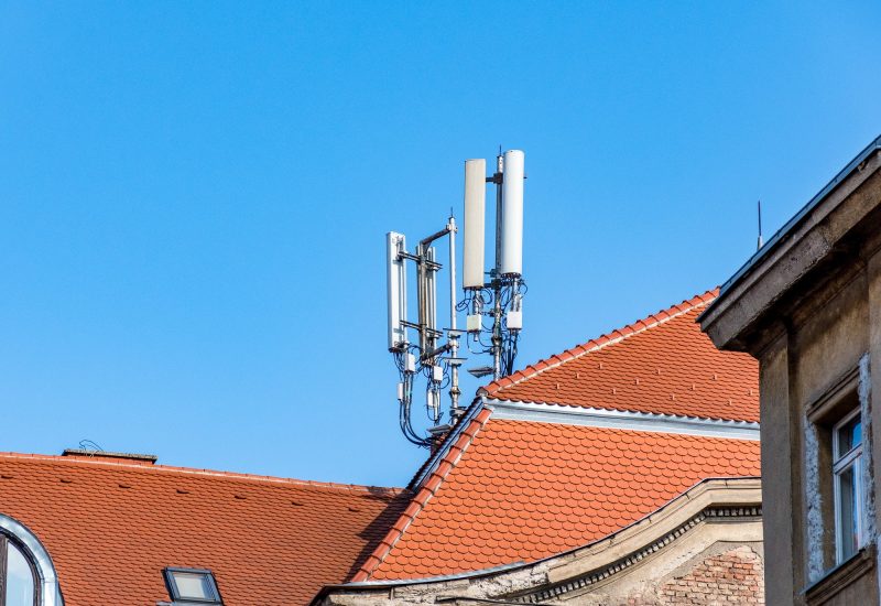 Mobile network cell tower on roof of building in city.